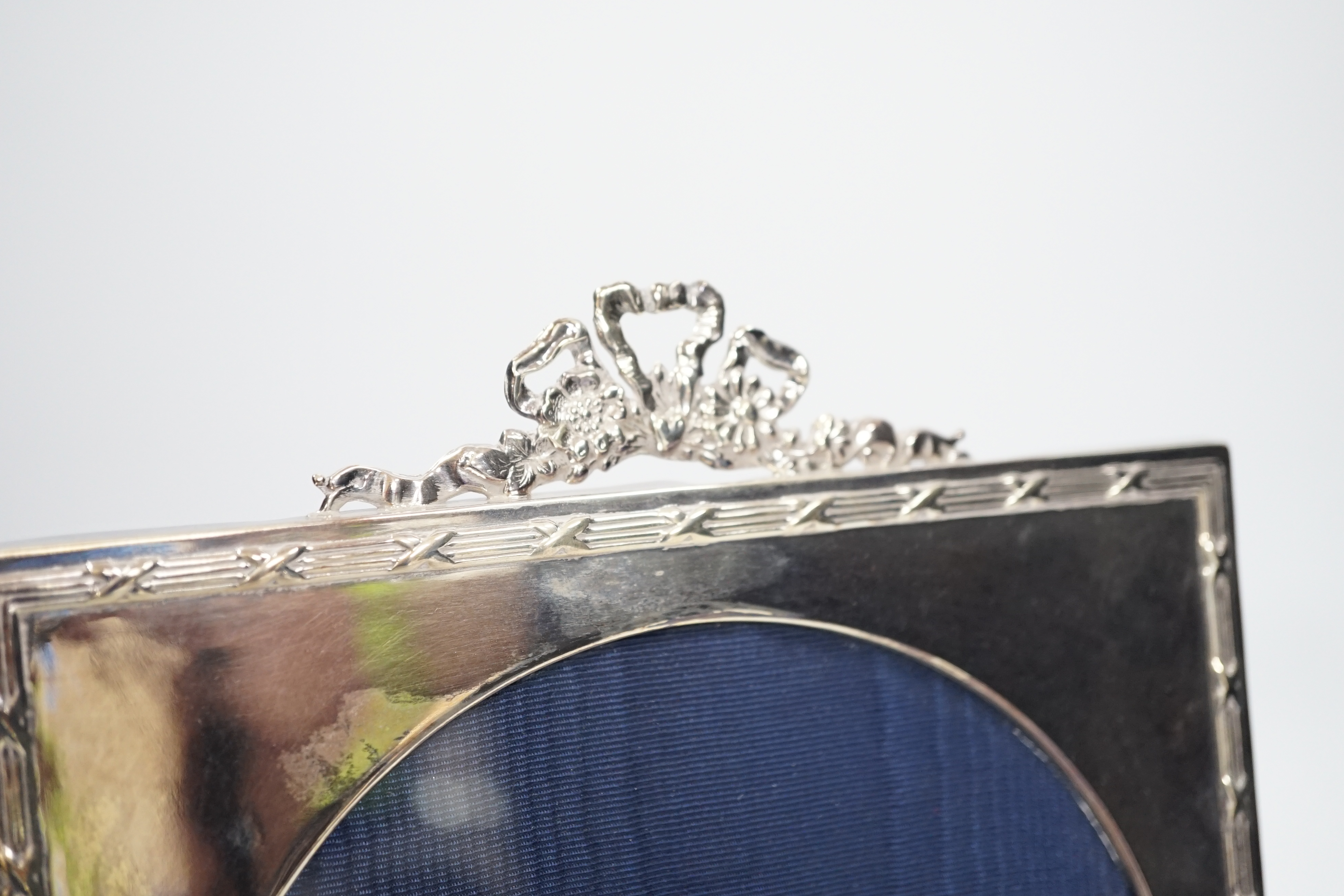 An Edward VII silver easel photograph frame with ribbon crest and circular aperture, Chester 1906, 20cm